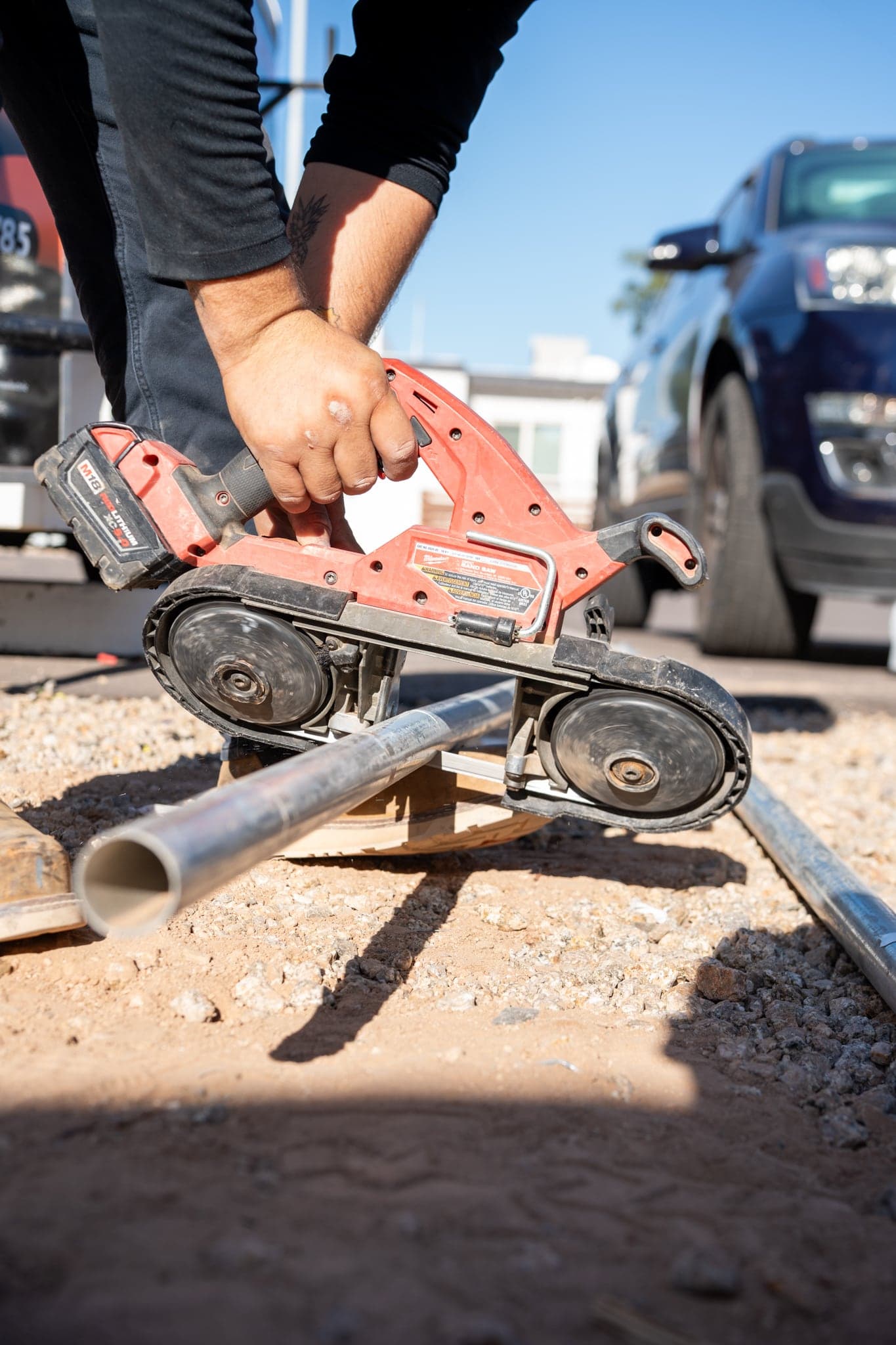 A technician cutting metal conduit with a cordless band saw