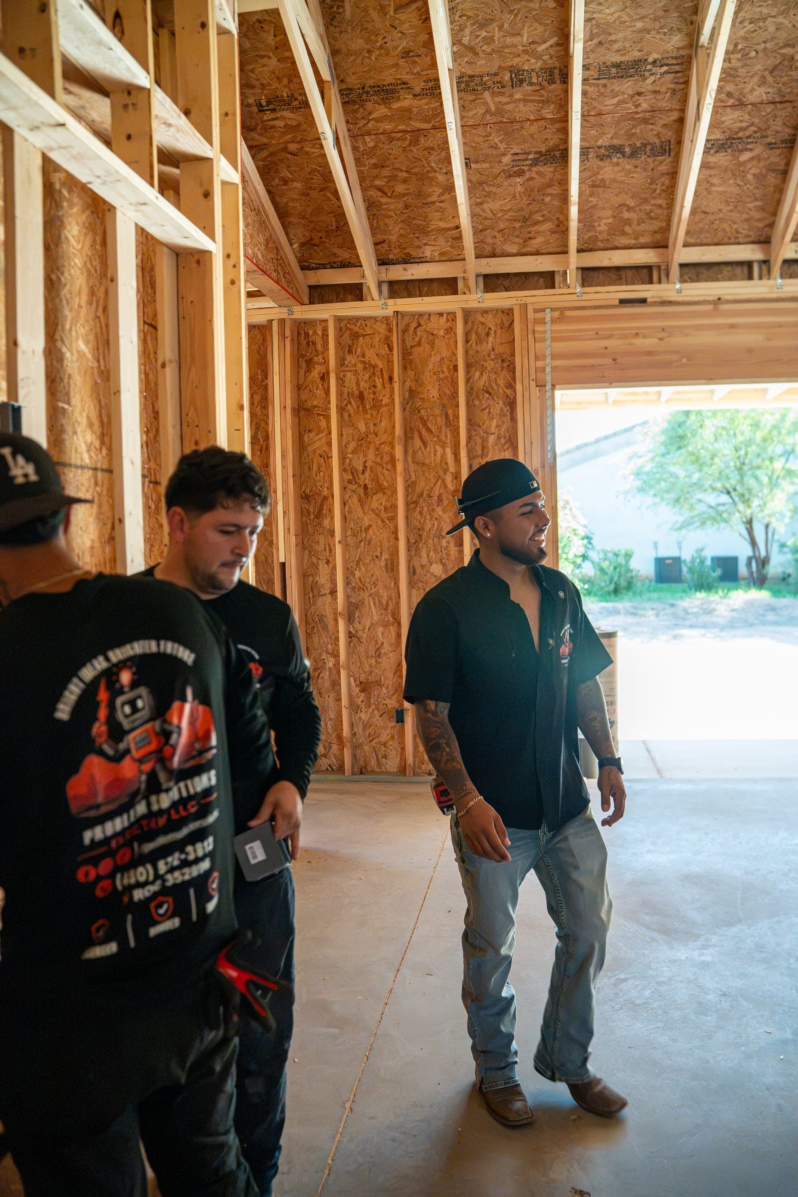 Three crew members talking inside the framed garage bay of a new house