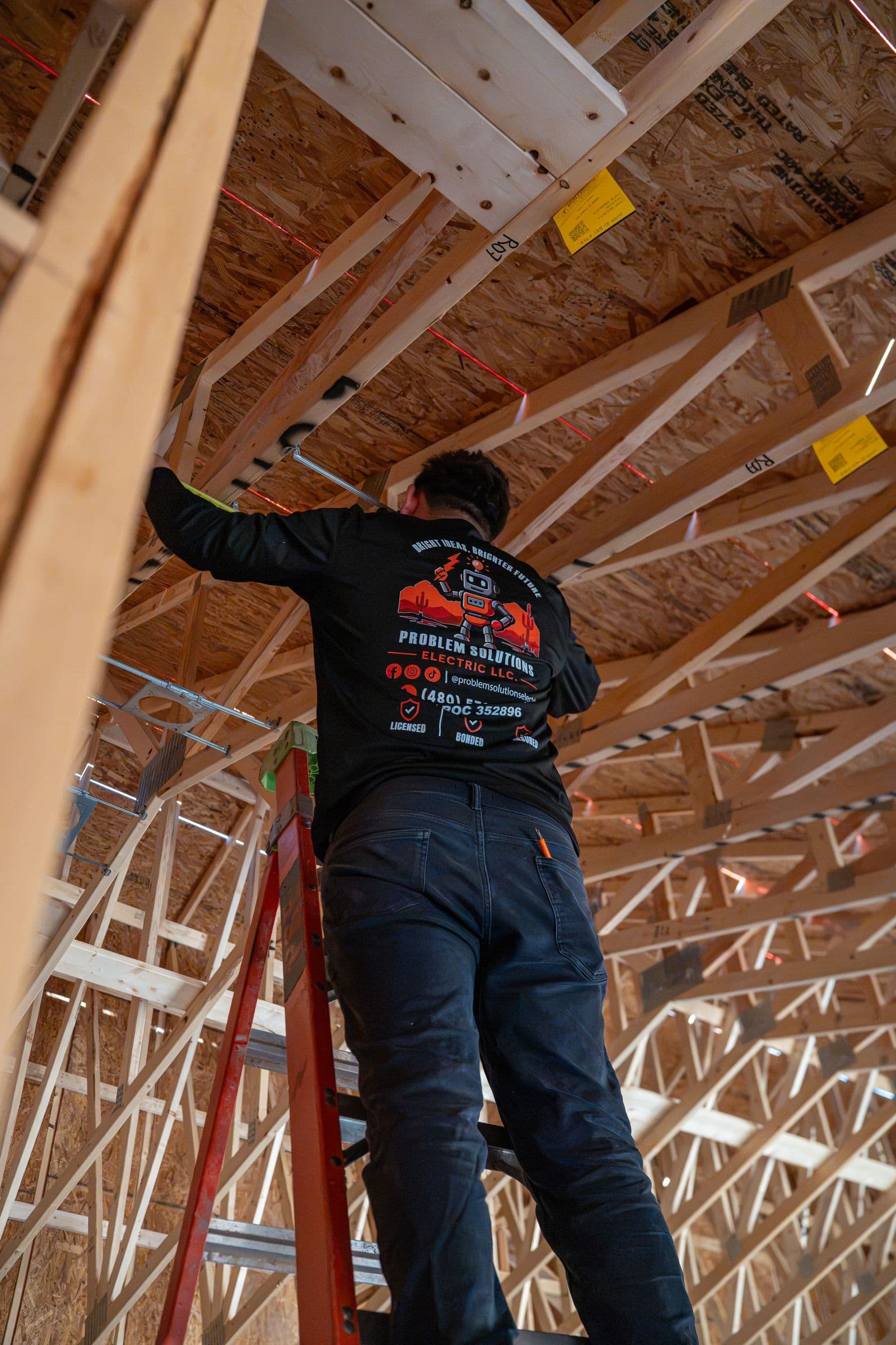 A technician on a ladder in the trusses