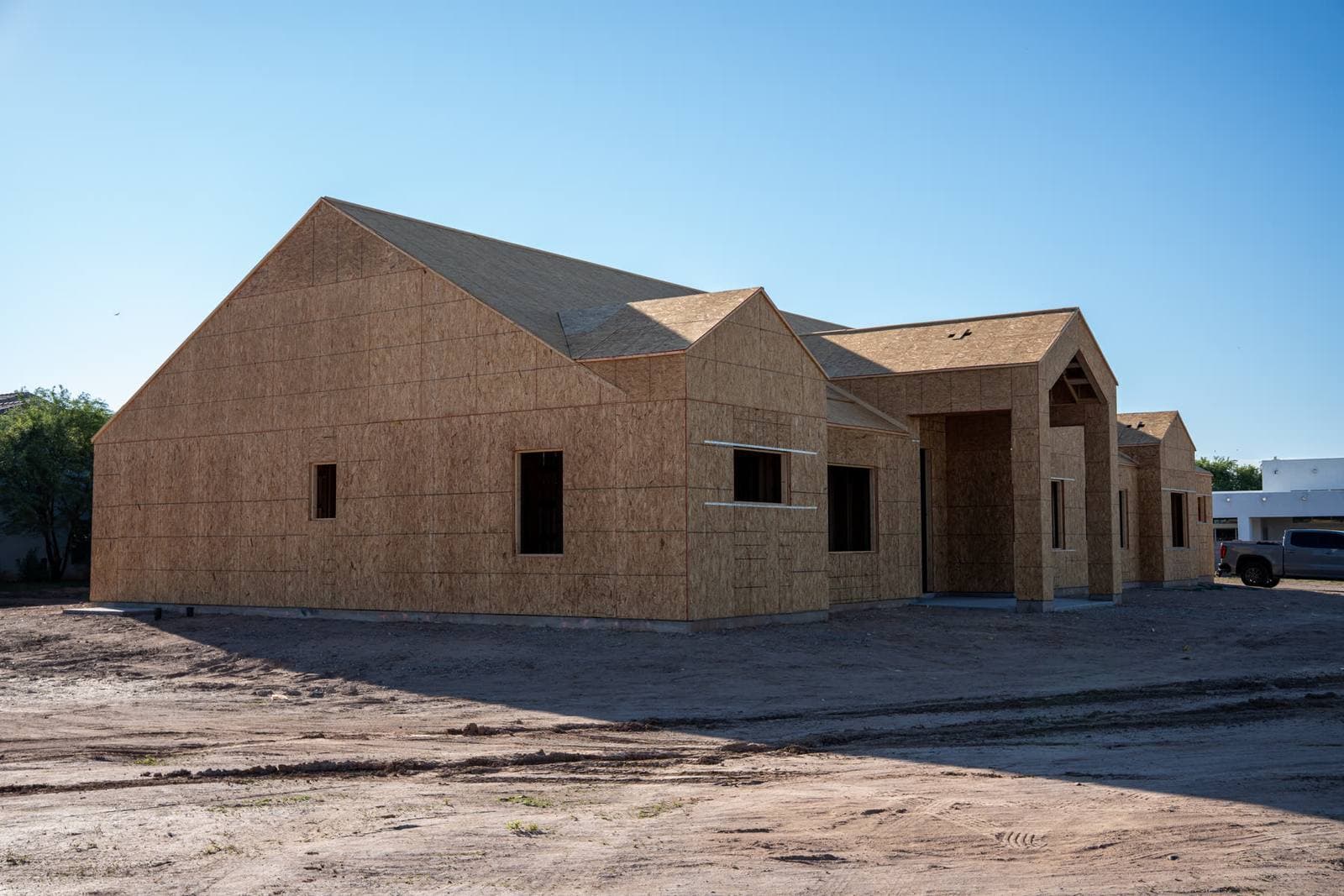 A new framed house from the side, sheathed walls and roof on a dirt lot