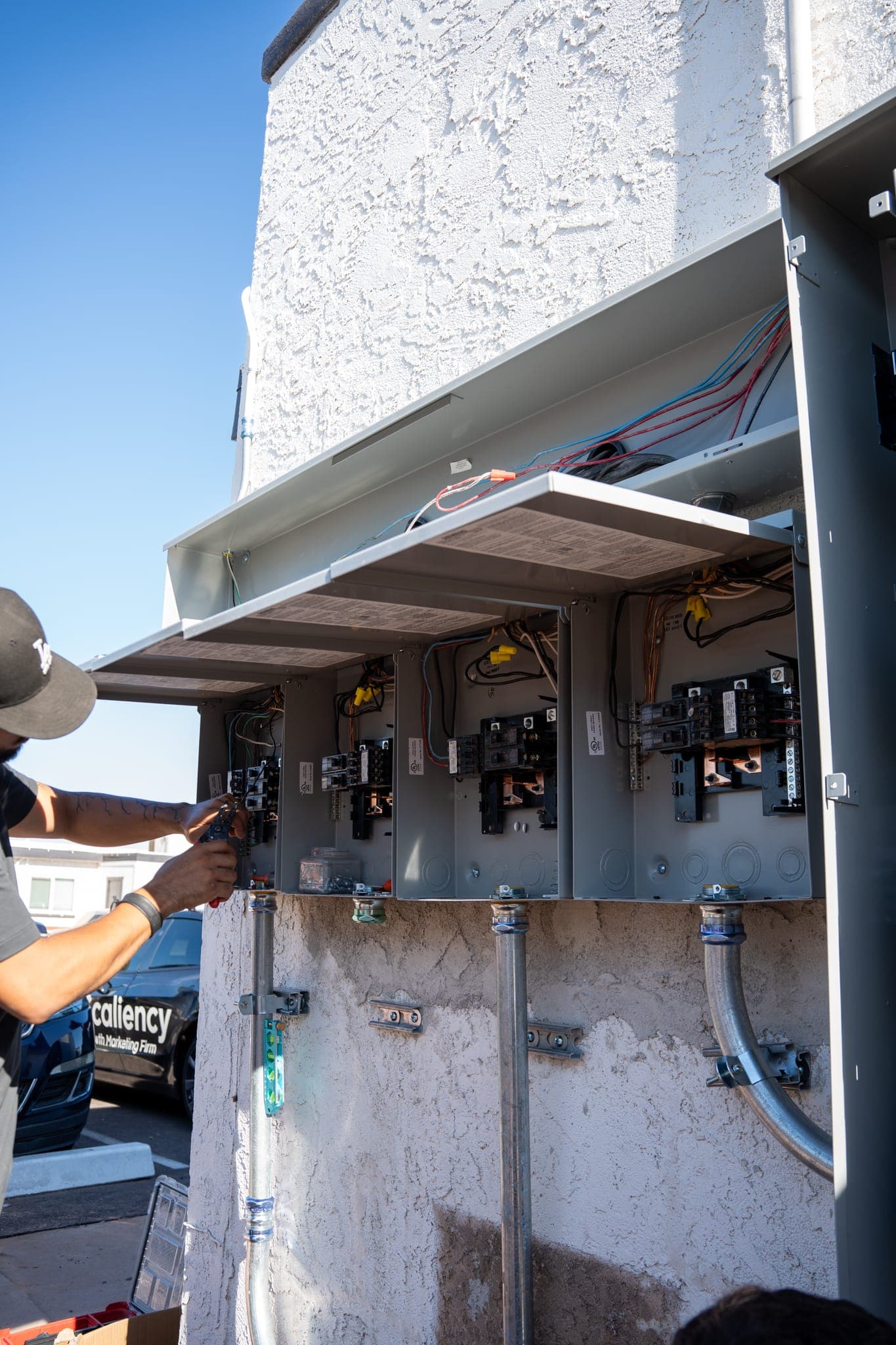 A row of open panels with the covers up, a technician reaching into the first one