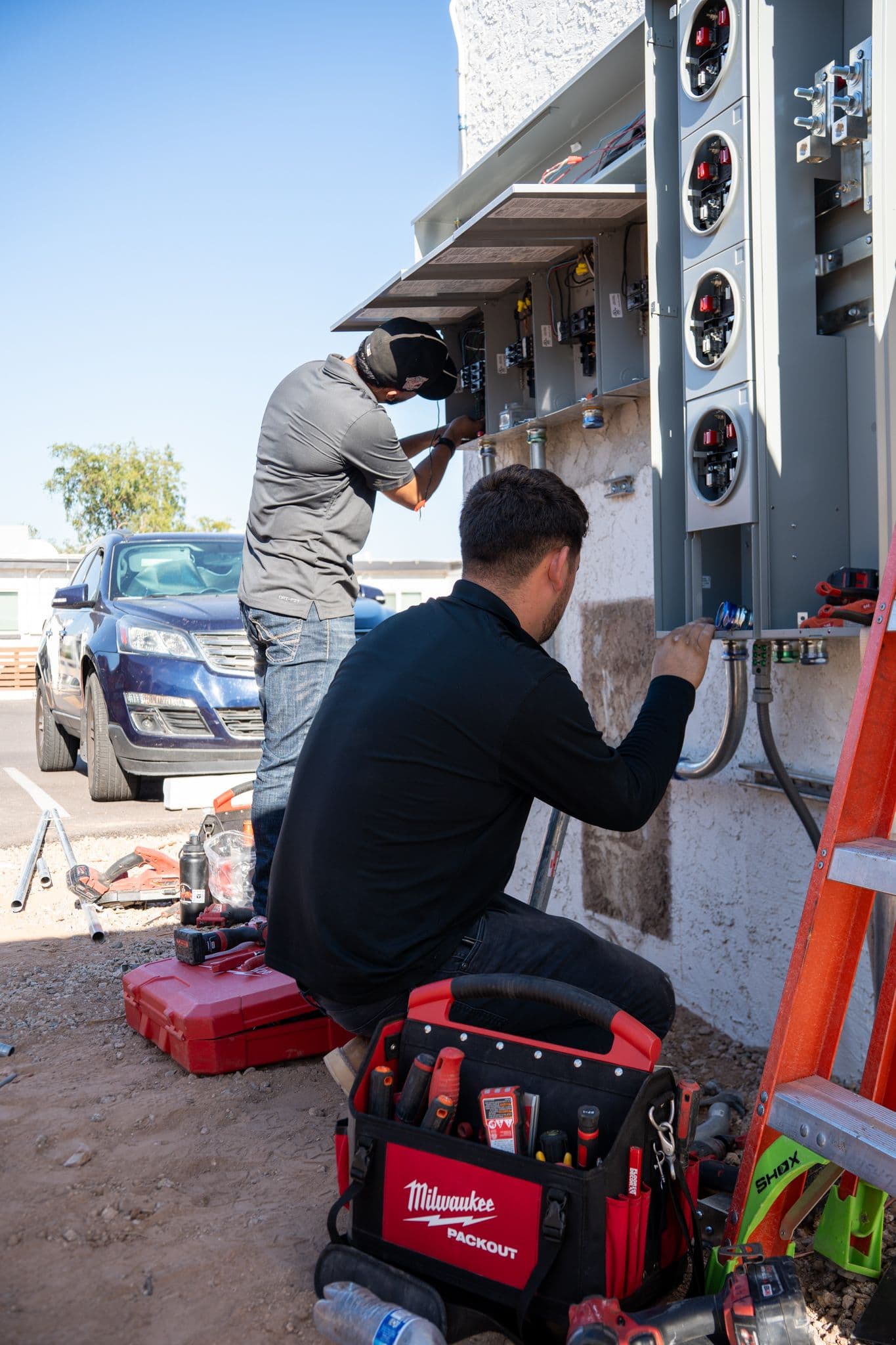 Two technicians working at the meter stack and panels