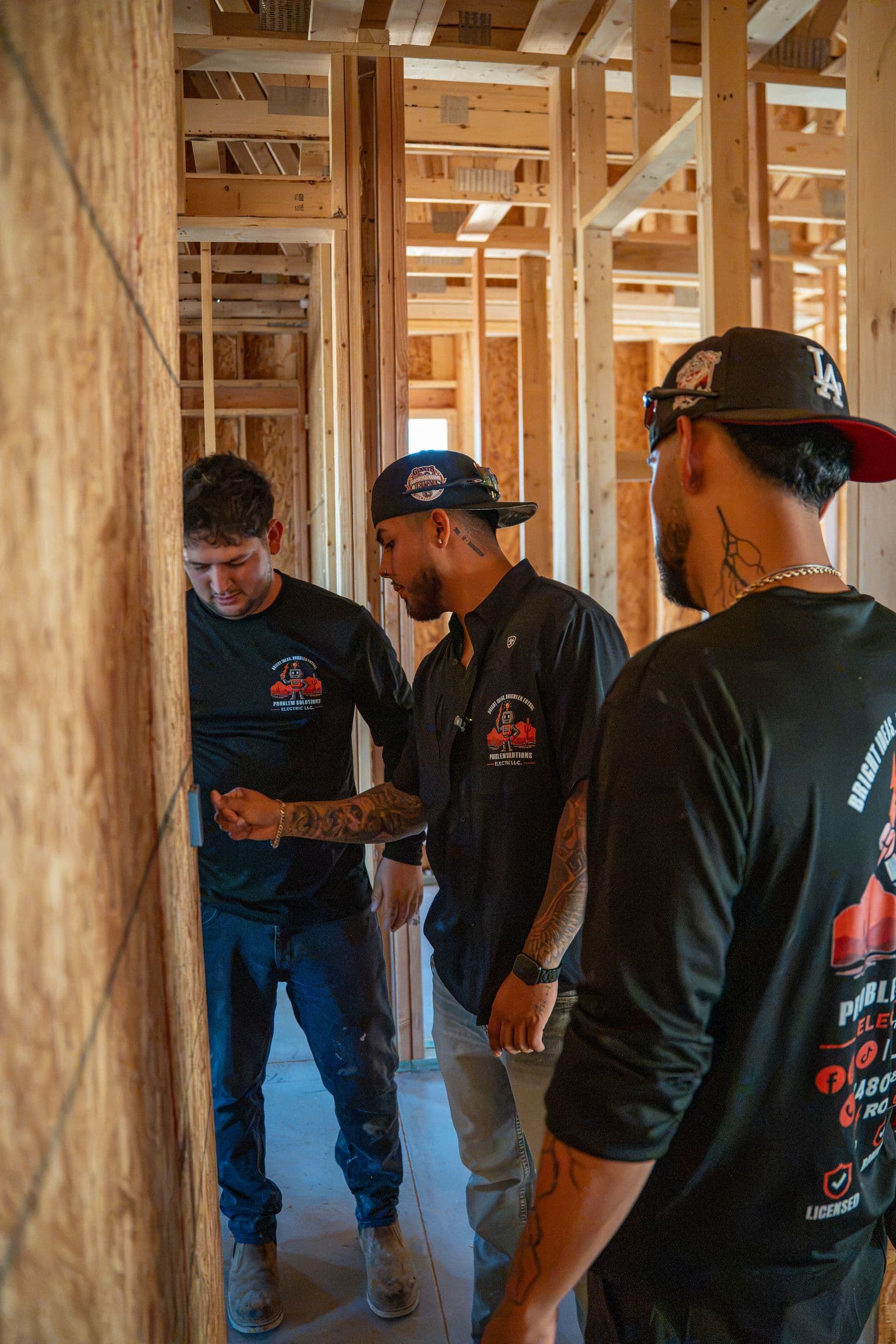 Three technicians talking through the work at a framed wall